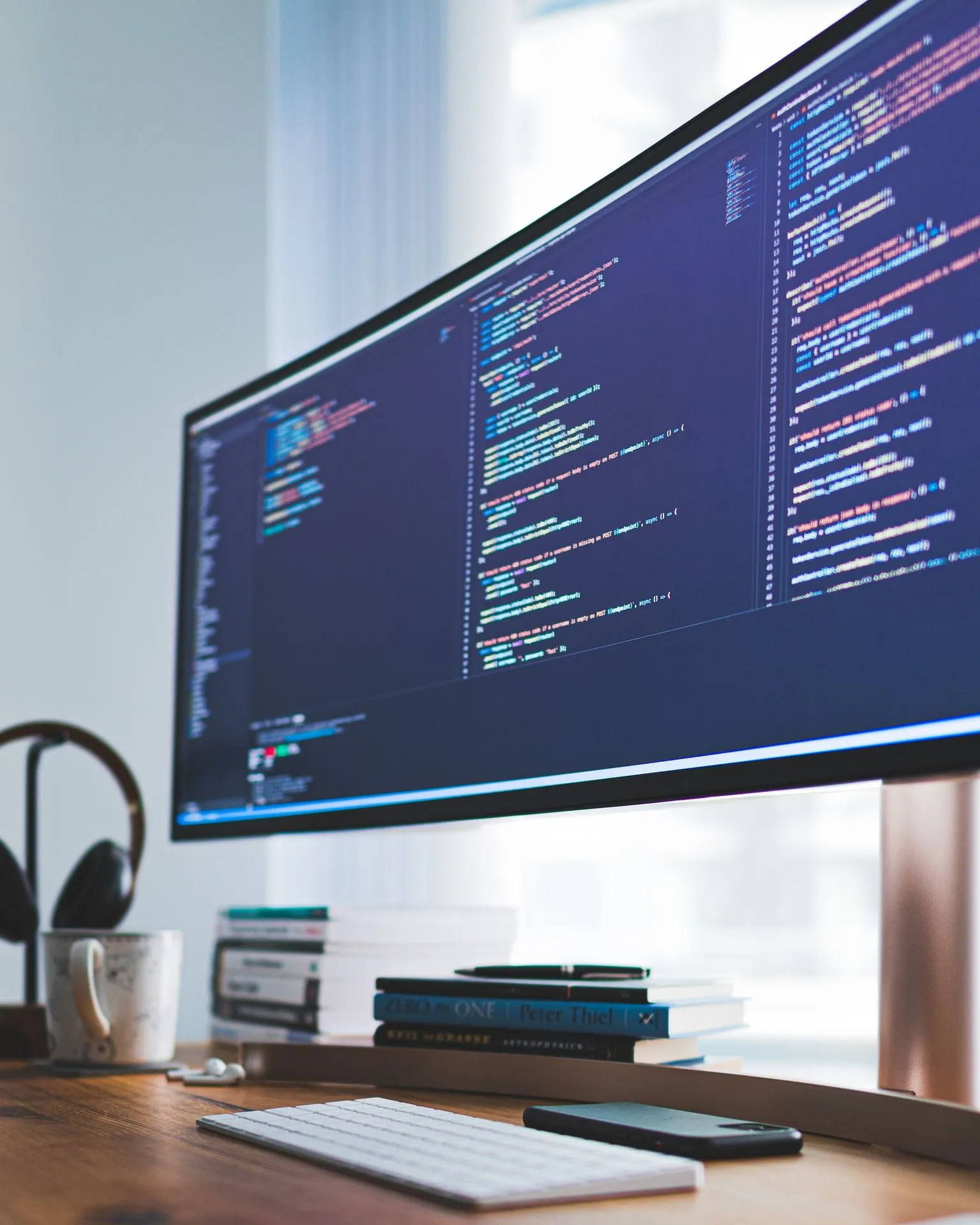 Wide monitor showing source code on a desk